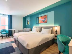 a bedroom with a large bed and a blue wall at Holyrood Aparthotel in Edinburgh