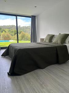 a black bed in a room with a large window at Coura Lodge in Paredes de Coura