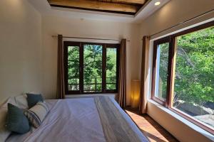 a bedroom with a bed and a large window at Paldan Orchids in Leh