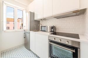 a kitchen with white cabinets and a stove top oven at GuestReady - Urban Garden Apartments in Lisbon