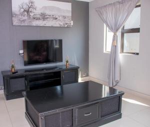 un soggiorno con TV e tavolo nero di The homestead resort a Mabhoko