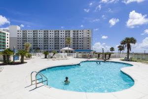 a swimming pool in front of a large building at Plantation Dunes Condos in Gulf Shores +44 photos