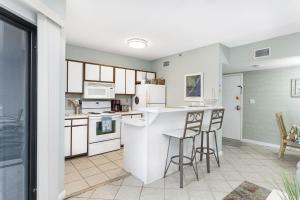a kitchen with white appliances and bar stools at Plantation Dunes Condos in Gulf Shores