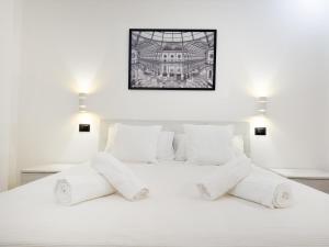 a white bedroom with a white bed with white pillows at Vigentino Suites in Milan