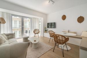 a living room with a couch and a table and chairs at Luxe zeeverblijf op 1min van het strand - 5p in Knokke-Heist