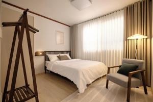 a bedroom with a bed and a chair and a window at Your-jin stay Seoul in Seoul