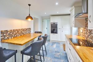 a kitchen with white cabinets and a wooden counter top at Host & Stay - Kenmore in Corbridge +6 photos