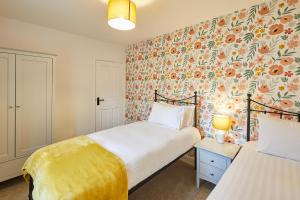 a bedroom with two beds and a floral wallpaper at Host & Stay - Kenmore in Corbridge