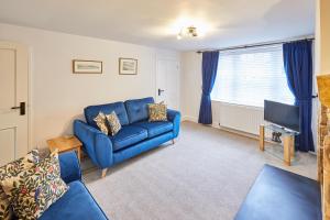 a living room with a blue couch and a tv at Host & Stay - Kenmore in Corbridge
