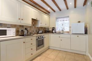 a kitchen with white cabinets and a white microwave at Brackendale Cottage Upperdale Peak District in Cressbrook