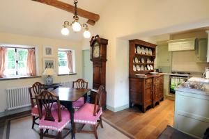 a kitchen with a table and chairs and a clock at Park CottageChatsworth Estate in Baslow