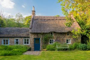 an old stone cottage with a thatched roof at Park CottageChatsworth Estate in Baslow