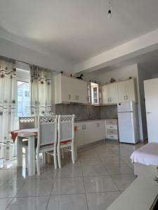 Una cocina con gabinetes blancos y una mesa y sillas. en Vila Viktori, en Ksamil