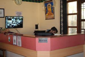 a man sitting at a reception counter in a restaurant at Hotel Spiti Heritage in Kaza