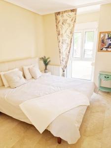 Una cama blanca grande en un dormitorio con ventana. en Always sunny apt PoolGolfBeach, en Alicante