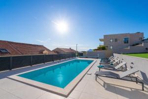 a swimming pool with lounge chairs next to a building at Villa Sunset Dubrovnik in Dubrovnik