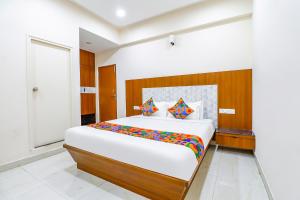 Un dormitorio con una gran cama blanca con almohadas de colores. en FabExpress Sathya Comforts - Nr Commercial Street, en Bangalore