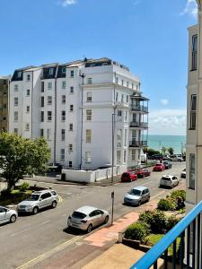 a large white building with cars parked in a parking lot at Vernon Guesthouse in Eastbourne