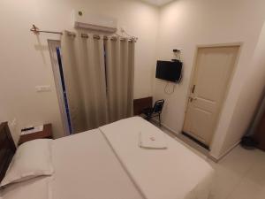 a bedroom with a bed and a door with a curtain at MITRA HOTELS in Mysore