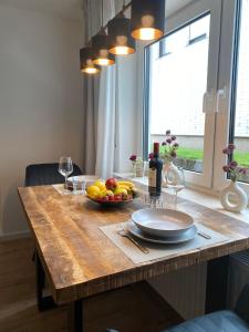 a wooden table with a bowl of fruit and wine glasses at Ferienwohnung Katharina in Mastershausen