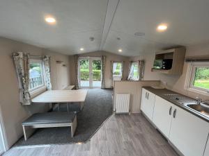 a kitchen with white cabinets and a table in a caravan at Newton Stewart - Lodge - Sleeps 4 - Garden in Bargrennan