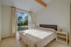 une chambre avec un lit et une grande fenêtre dans l'établissement Les Appartements et Maisons du Domaine de Saint Endréol Golf & Spa Resort, à La Motte