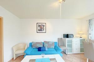 een woonkamer met een blauwe bank en een tafel bij Haus Antje Gartenbungalow in Kolpinsee
