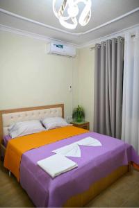Un dormitorio con una cama grande con una manta morada. en Vila BENE, en Pogradec