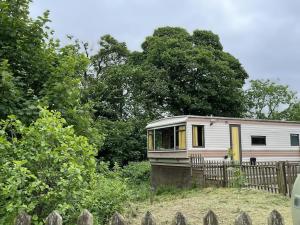 a small white trailer parked in front of a fence at Hare Meadow Lodge in Mellor