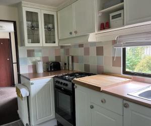 a kitchen with white cabinets and a stove top oven at Hare Meadow Lodge in Mellor