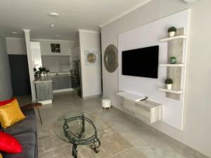 a living room with a couch and a tv on a wall at Zest Apartment in Gaborone