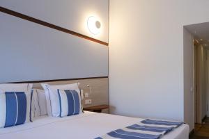 a bedroom with a bed with blue and white pillows at Hotel Blaumar Cadaqués by Fimedhotels in Cadaqués