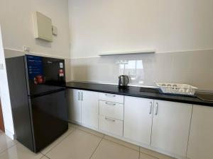 a kitchen with a black refrigerator and white cabinets at Le Pavilion Puchong 10pax 3R2B in Puchong
