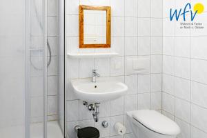a bathroom with a sink and a toilet and a mirror at Ferienhaus am Gutspark Drankse Ferienwohnung Weißdorn in Dranske