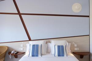 a bedroom with a bed with blue and white pillows at Hotel Blaumar Cadaqués by Fimedhotels in Cadaqués