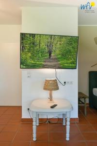 a lamp on a table with a tv on a wall at Ferienhaus am Gutspark Drankse Ferienwohnung Heiderose in Dranske