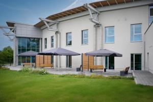 OschatzHostel Oschatz的一群长椅,上面有雨伞,在建筑前