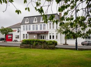 a large white building on a street with a green field at The Carrigart Hotel in Carrigart