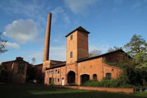 an old brick building with a tall chimney at Modernes Tiny House in historischem Ambiente in Neu Kaliß