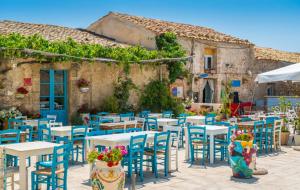 un groupe de tables et de chaises devant un bâtiment dans l'établissement casa del corso, à Canicattini Bagni