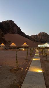 a row of tents in a desert with a mountain at Yellow Star Camp Wadi Rum in Wadi Rum +105 photos