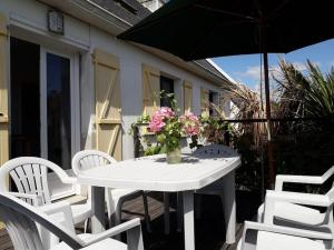 a white table and chairs with a vase of flowers at Maison de vacances à Névez Des Lys d'Océan in Névez