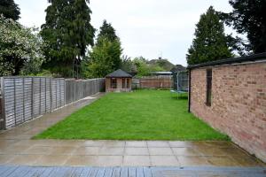 a garden with a brick wall and a fence at Instant Home in Luton