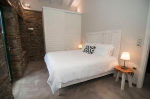 a bedroom with a white bed and a table with a lamp at Nephelis Heritage House in Moúdhros
