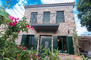 an old stone house with green shutters and flowers at Nephelis Heritage House in Moúdhros