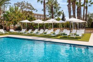 a pool with lounge chairs and umbrellas at Meliá Lloret de Mar in Lloret de Mar