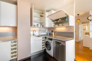 a kitchen with white cabinets and a washer and dryer at GuestReady - A Spacious apt near Eiffel Tower in La Défense