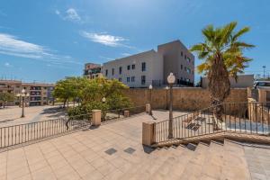 a walkway with a fence and palm trees and buildings at L'Alcor Aparthotel in Alicante