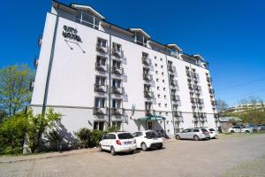 a large white building with cars parked in a parking lot at City Hotel Bucharest in Bucharest