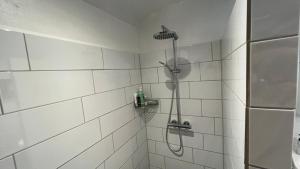a white tiled shower with a shower head in a bathroom at Staudeengen et dejlig sted med fred og ro in Ålestrup +27 photos